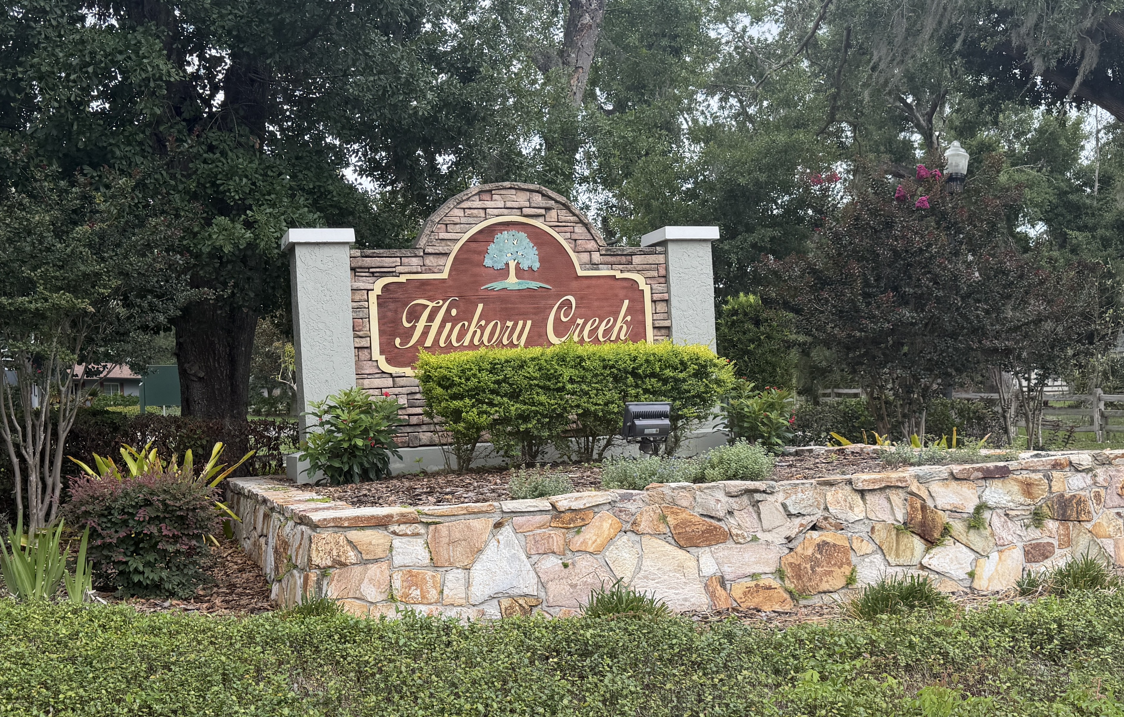 Hickory Creek entrance monument with oak tree landscaping